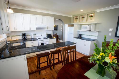 a kitchen with white cabinets and a table with a vase of flowers at Hume Hotel & Spa in Nelson