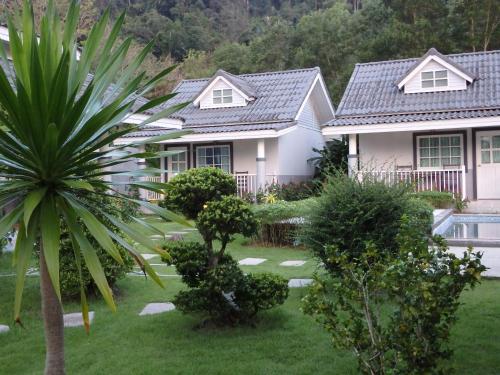 a house with a palm tree in front of a yard at Suksompong Resort in Khao Lak