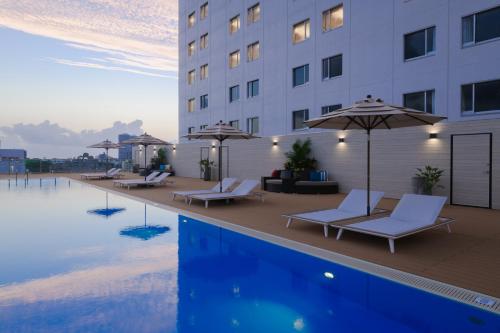 a hotel pool with chairs and umbrellas next to a building at Novotel Okinawa Naha in Naha