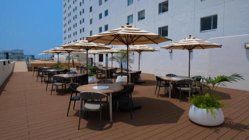 a deck with tables and chairs with umbrellas at Novotel Okinawa Naha in Naha