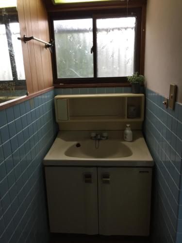 La salle de bains est pourvue d'un lavabo et d'une fenêtre. dans l'établissement Ibusiki Chinese Minshuku, à Ibusuki