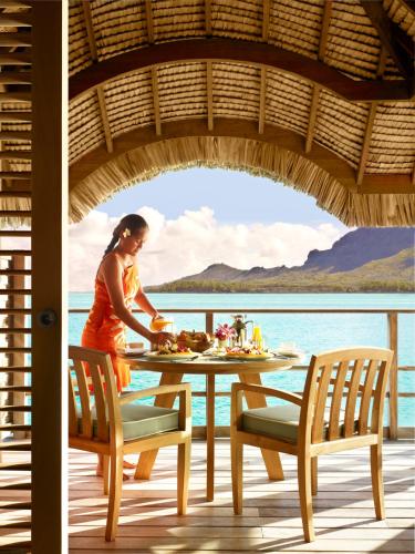 a woman preparing food on a table on a deck at Four Seasons Resort Bora Bora in Bora Bora