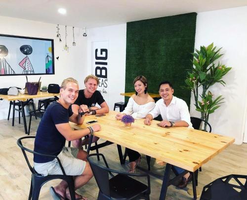 a group of people sitting around a wooden table at Murals Hostel and Cafe in Cebu City