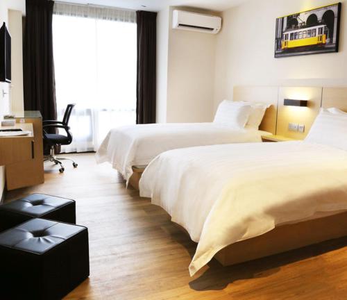 a hotel room with two beds and a desk at Rivertel in Teluk Intan