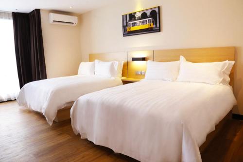 two beds in a hotel room with white sheets at Rivertel in Teluk Intan