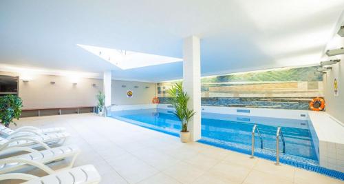 a large swimming pool with white chairs and a blue swimming pool at Premier Kraków Hotel in Kraków