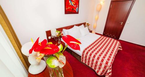 a bedroom with a bed and a vase of flowers at Premier Kraków Hotel in Kraków