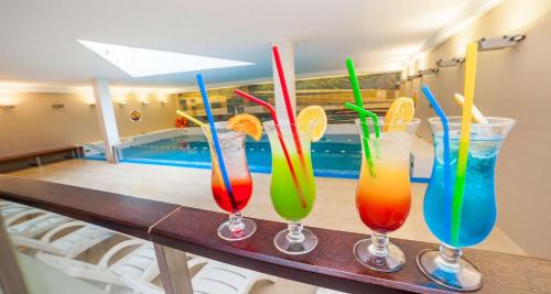 four colorful drinks sitting on a table next to a swimming pool at Premier Kraków Hotel in Kraków