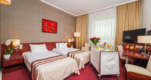 a hotel room with two beds and a desk at Premier Kraków Hotel in Kraków