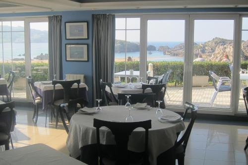 a restaurant with tables and chairs and a large window at Hotel Pineda Playa in Noja