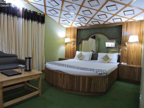 a bedroom with a bed and a couch and a table at Hotel Chaman Palace in Shimla