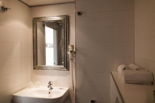 a white bathroom with a sink and a mirror at City Hotel Tilburg in Tilburg