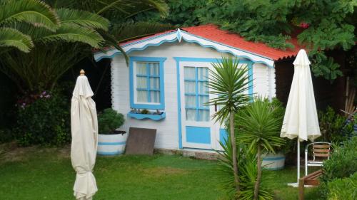 a small house with a blue door and two umbrellas at Hotel Pineda Playa in Noja