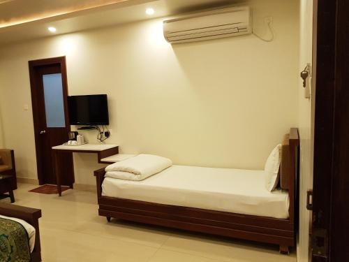 a bedroom with a bed and a desk with a television at Hotel Banaras Haveli in Varanasi