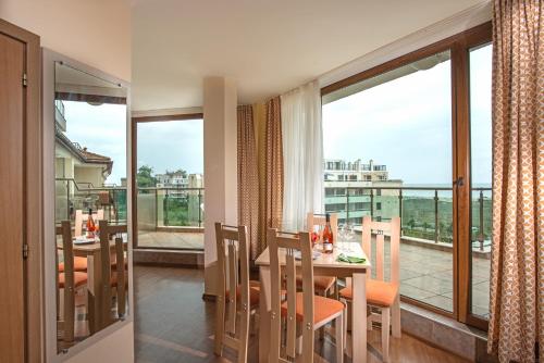 a dining room with a table and chairs and a balcony at Aparthotel Hotel Prestige City II in Primorsko