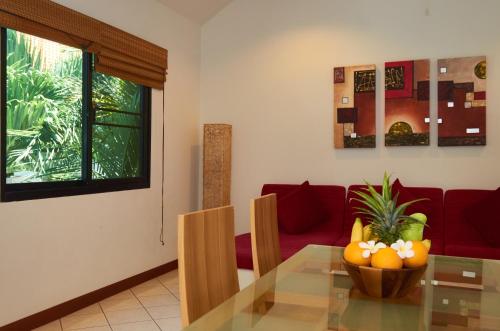 a living room with a glass table and a red couch at Phuket Riviera Villas - SHA Extra Plus in Nai Harn Beach