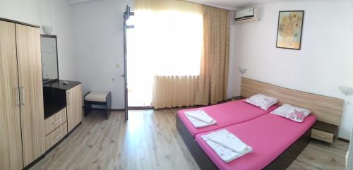 1 dormitorio con cama rosa y TV en Villa Diana en Kiten