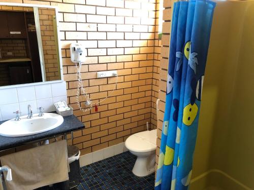 a bathroom with a toilet, sink, and bathtub at Stockman Motor Inn in Narromine