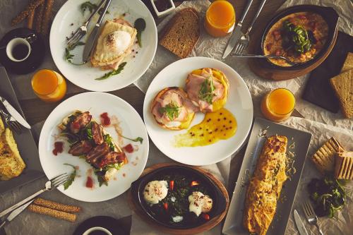 una mesa cubierta con platos de comida y naranjas en The Artist Athens, en Atenas