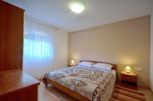 een slaapkamer met een bed met 2 lampen en een raam bij Apartment Nada with Private Pool in Buzet