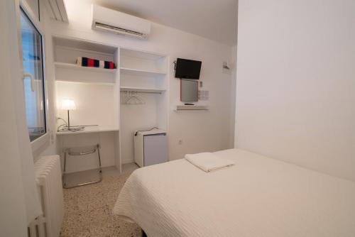 a white bedroom with a bed and a desk at Hostal Marina Cadaqués in Cadaqués