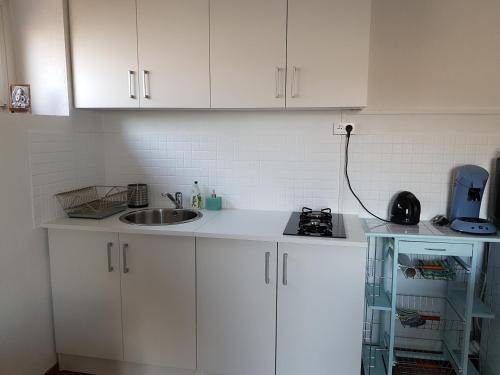 a kitchen with white cabinets and a sink at Le Domaine des Prés in Lachambre