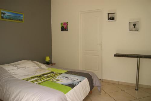 ein Schlafzimmer mit einem Bett und einem Tisch und einer Tür in der Unterkunft Caribanou in Le Gosier