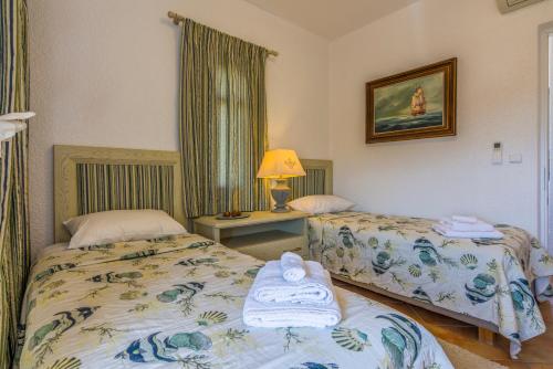 a bedroom with two beds and a table with a lamp at Elaia Villas in Pythagoreio