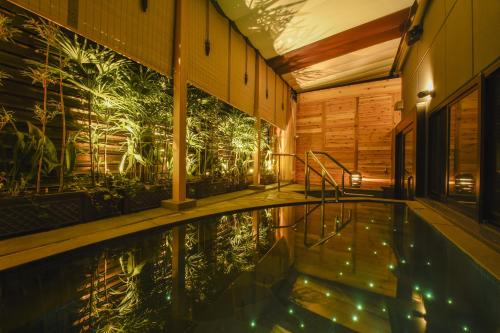 a swimming pool in a building with a mural of plants at Capsule Hotel Anshin Oyado Premium Resort Kyoto Shijo Karasuma in Kyoto