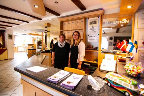 a man and woman standing at a counter in a restaurant at Landgasthof Hotel Will in Neuenstein