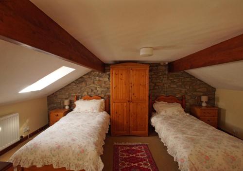 a bedroom with two beds and a stone wall at Ty Clyd in Cross Inn