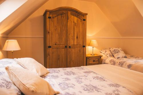 a bedroom with two beds and a wooden cabinet at The Mouries Holiday Cottage in Fochabers