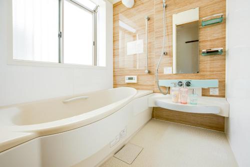bagno bianco con lavandino e specchio di JIYUKA INN a Izumisano