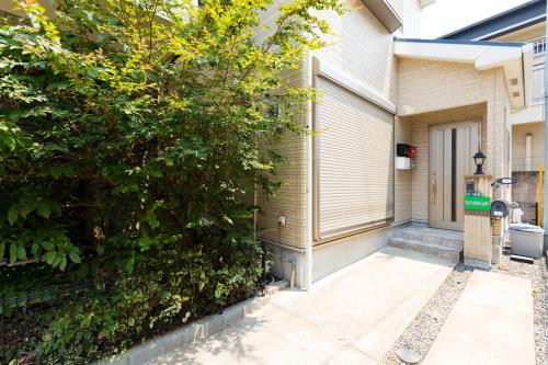 a house with a tree next to a door at JIYUKA INN in Izumi-Sano