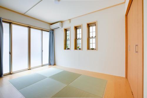 una stanza vuota con finestre e una parete bianca di JIYUKA INN a Izumisano