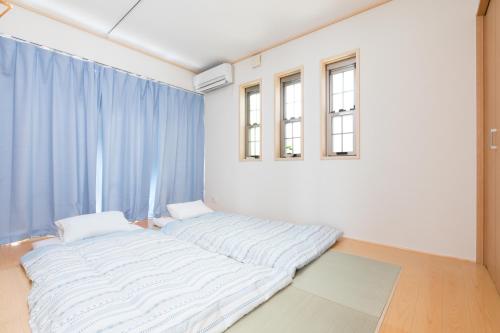 a bed in a room with blue curtains at JIYUKA INN in Izumi-Sano