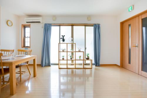 a dining room with a table and blue curtains at JIYUKA INN in Izumi-Sano