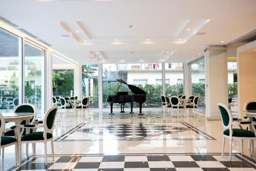 a grand piano in a room with chairs and tables at Hotel Terme Venezia in Abano Terme