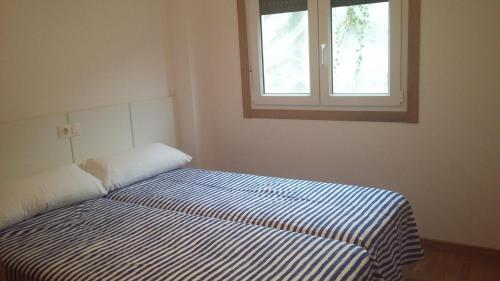 1 cama en un dormitorio con ventana en Grupoele3 Edificio Camposiño, en Finisterre
