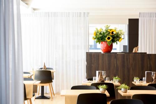 a room with tables and chairs and a vase of flowers at Hotel Nelson in Knokke-Heist