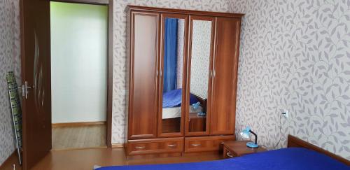 a bedroom with a wooden cabinet with a mirror at Apartment Rustaveli 59 in Batumi