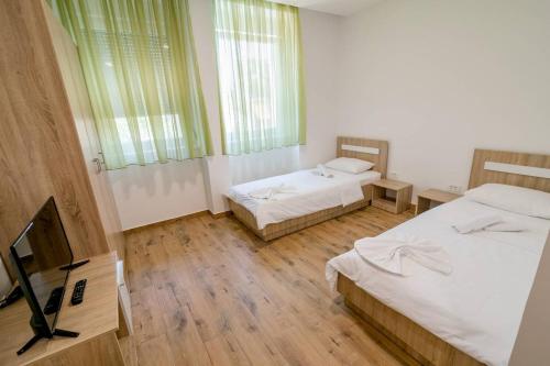 a room with two beds and a flat screen tv at Apartmani Luka Meljine in Meljine