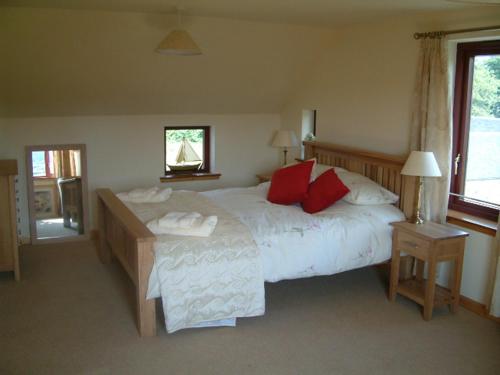 トバモーリにあるGamekeeper's Cottageのベッドルーム(赤い枕の大きな白いベッド付)