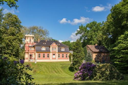 a large house on a grassy hill with a barn at Ferienwohnung "Schloss Kromlau" in Kromlau