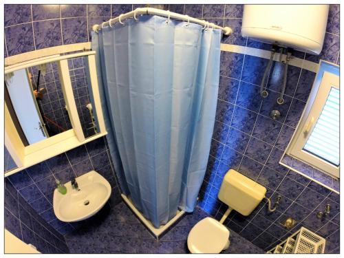 a bathroom with a blue shower curtain and a sink at Apartments Sara in Lopar