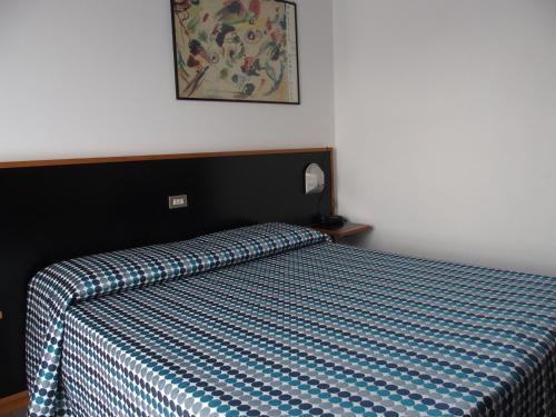 a bedroom with a bed with a blue and white bedspread at Hotel Eden in Orbassano