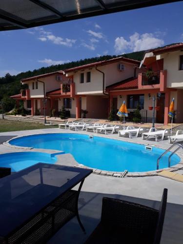 a large swimming pool with chairs and a building at Gledkata Complex in Skobelevo