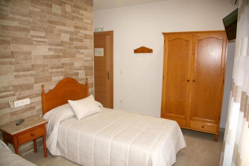 una camera da letto con un letto e un armadio in legno di Hostal Restaurante Grela a Pozo Alcón