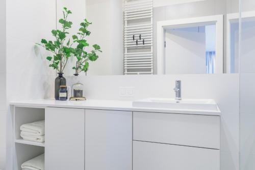 a white bathroom with a sink and a mirror at Novis Apartments Panorama View in Warsaw