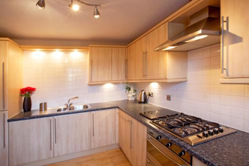 una cucina con armadi in legno e piano cottura. di A AAa a Edimburgo